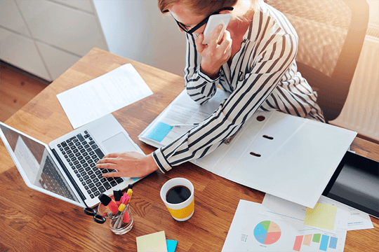 Woman working in office on phone and laptopn