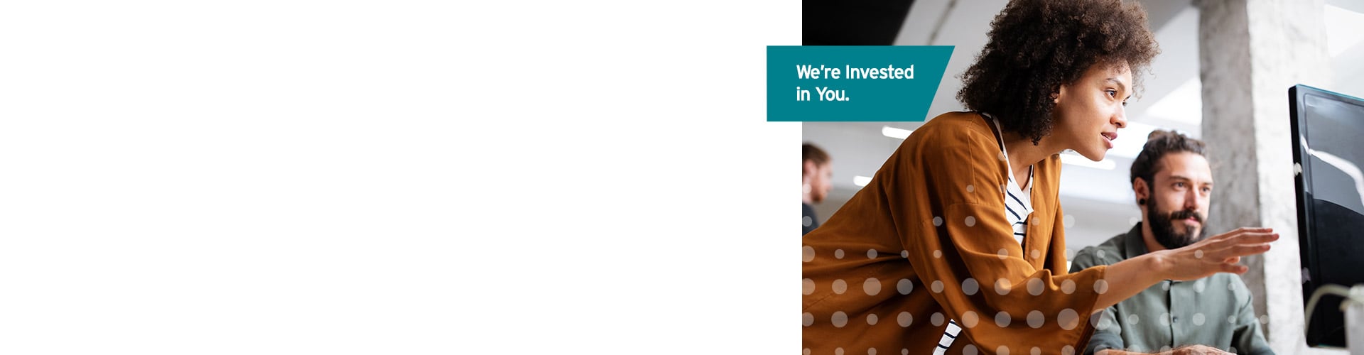 Teal label reads “We’re invested in you,” while a woman in a brown polka-dot blouse gestures toward screen beside a bearded colleague.