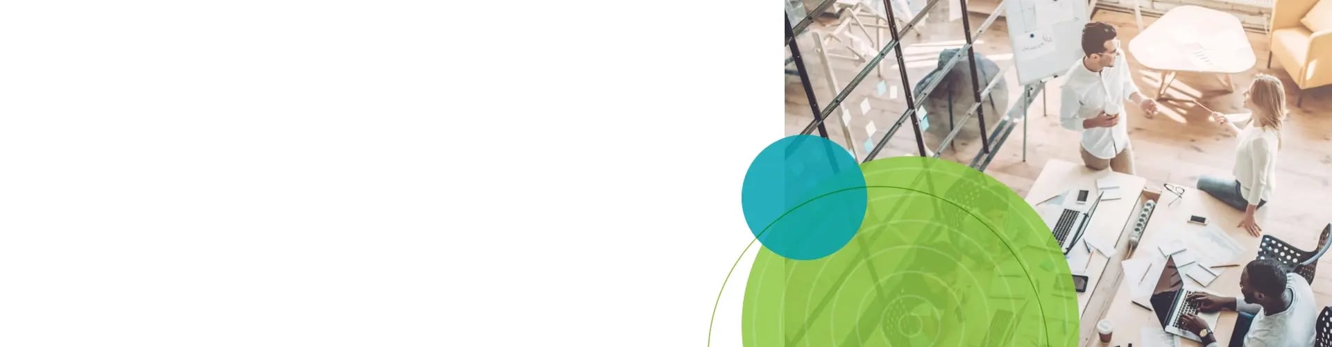 Overhead view of a small group collaborating in a modern office space, with laptops, documents, and notebooks spread across a large table.