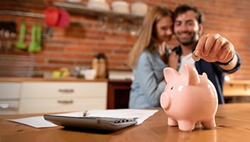 : father and daughter saving money in piggy bank