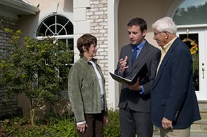 realtor talking to couple in front of house