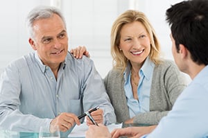 smiling elderly couple meeting with financial planner
