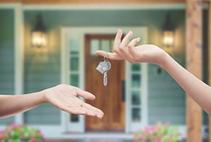 : keys handing over keys in front of house