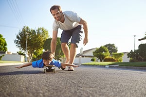 dad pushing son on skateboard