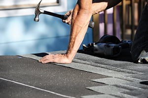 man hammering roof tiles