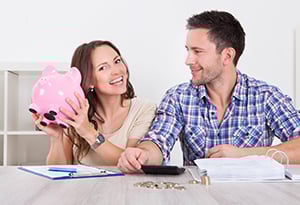 smiling couple with pink piggy bank of money