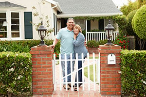 smiling retirees in front of new home