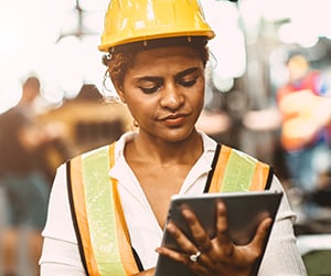 woman with hardhat and vest on tablet