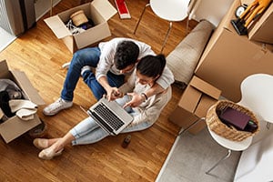 couple with moving boxes researching mortgage lenders