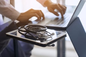 doctor typing on laptop with stethoscope