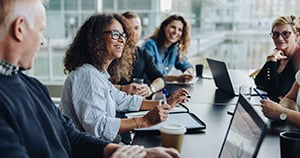 group of happy employees at a table on computers