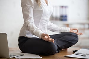 business woman sitting on her desk doing yoga