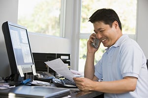 man smiling reviewing paperwork and on the phone