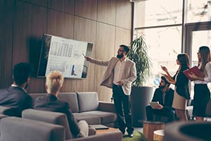 man presenting to business people using tv graphs