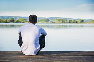 man sitting on a dock looking at a lake