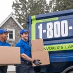 Two 1-800-GOT-JUNK employees carrying boxes out to truck