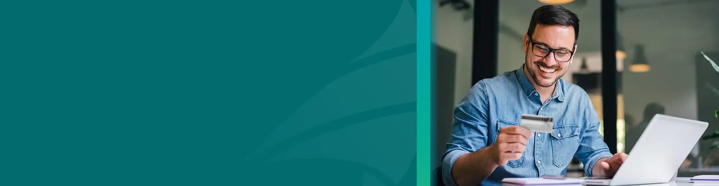 A person holding a credit card and looking at a computer