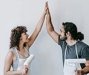 couple painting their home giving high five