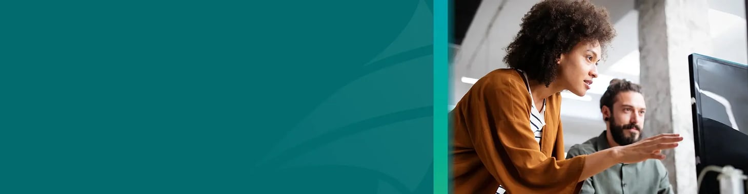 A small business owner pointing at a computer with employees.