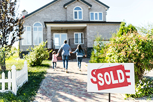 family walking toward house in rural area with sold sign