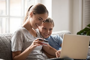 smiling woman and child using laptop and credit card