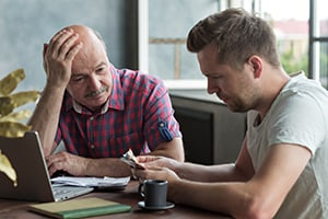 elderly man and son grimly reviewing paperwork