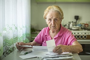 elderly woman grimly reviewing paperwork