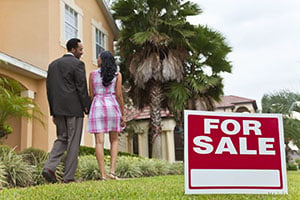 couple with their backs turned walking away from for sale sign