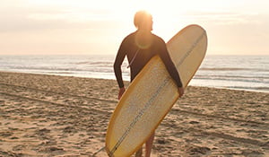 man on beach with surf board