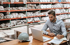 logistics manager on laptop in warehouse