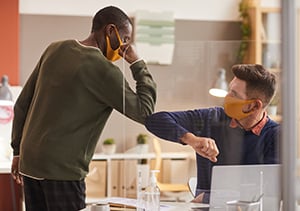 two professional men bumping elbows with masks on