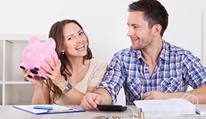 smiling couple with piggy bank of money