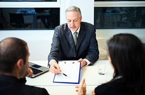 male banker going over business loan paperwork with couple