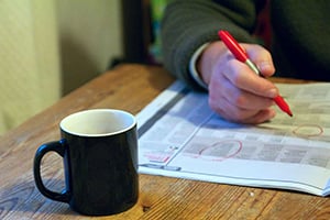 Man's hand reviewing newspaper with coffee cup