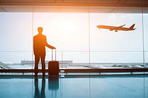 man at airport looking at plane taking off
