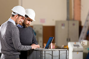 two men working on laptop with hard hats