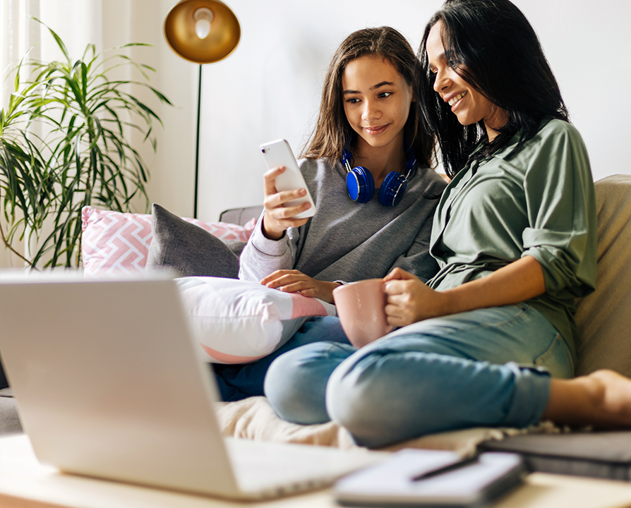 mother and daughter sitting on their couch looking at a smart phone