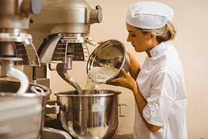 female baker mixing with large equipment